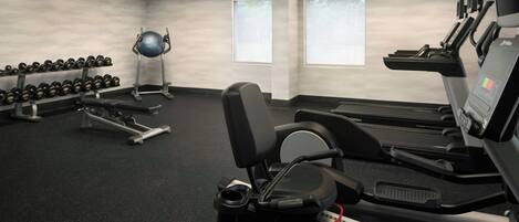 A gym with treadmills, dumbbells, and exercise balls.