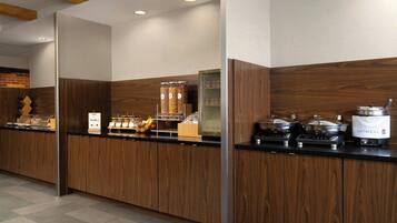 A buffet setup with wooden cabinets, a coffee machine, and a food display.