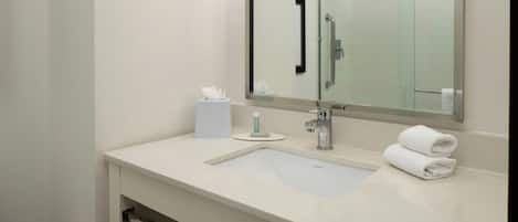 A modern bathroom with a large mirror, a sink, and a towel rack.