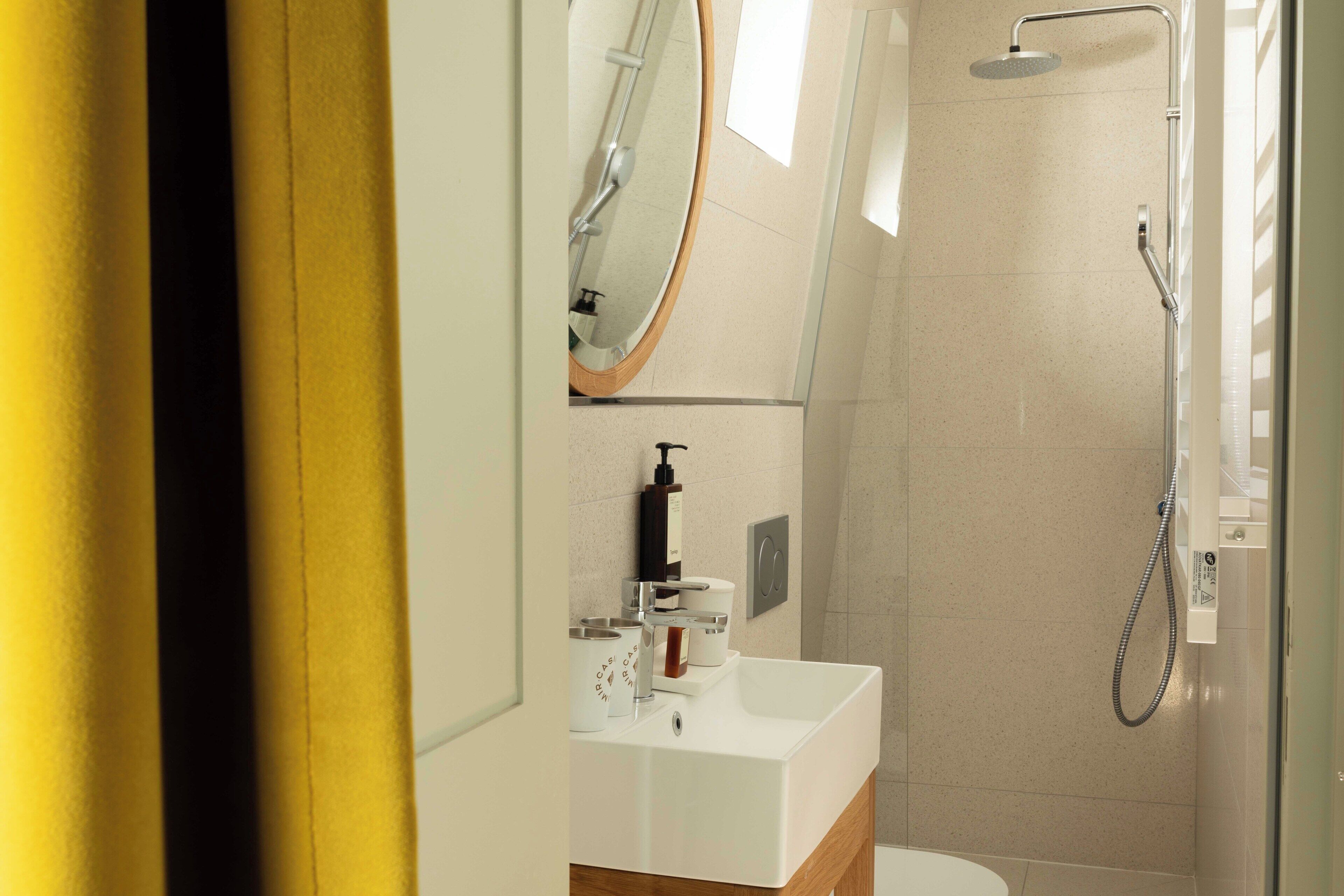 A modern bathroom with a white sink, mirror, and shower.