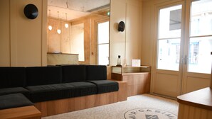 A reception area with a black sofa, wooden counter, and a patterned carpet with a logo. - Hotel Casimir (Paris)