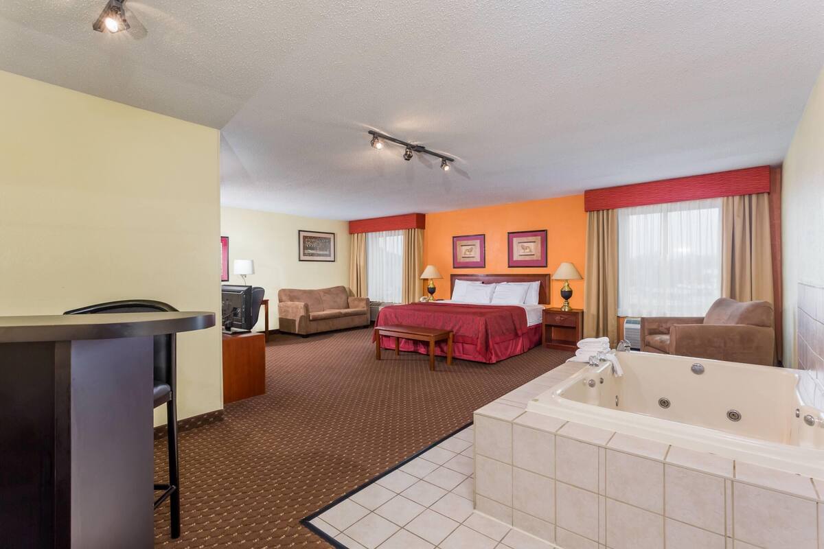 Une chambre d’hôtel équipée d’un lit, d’un bureau, d’une chaise, d’un canapé, d’une grande baignoire et d’un téléviseur.