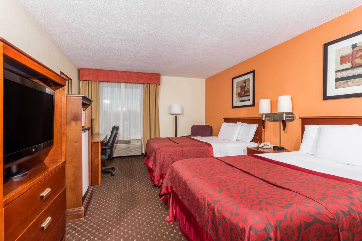 Une chambre d’hôtel avec deux lits, une télévision, un bureau et une chaise.