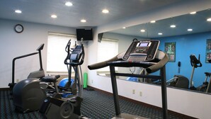 Un gimnàs amb equip de cardio, un rellotge i un mirall.