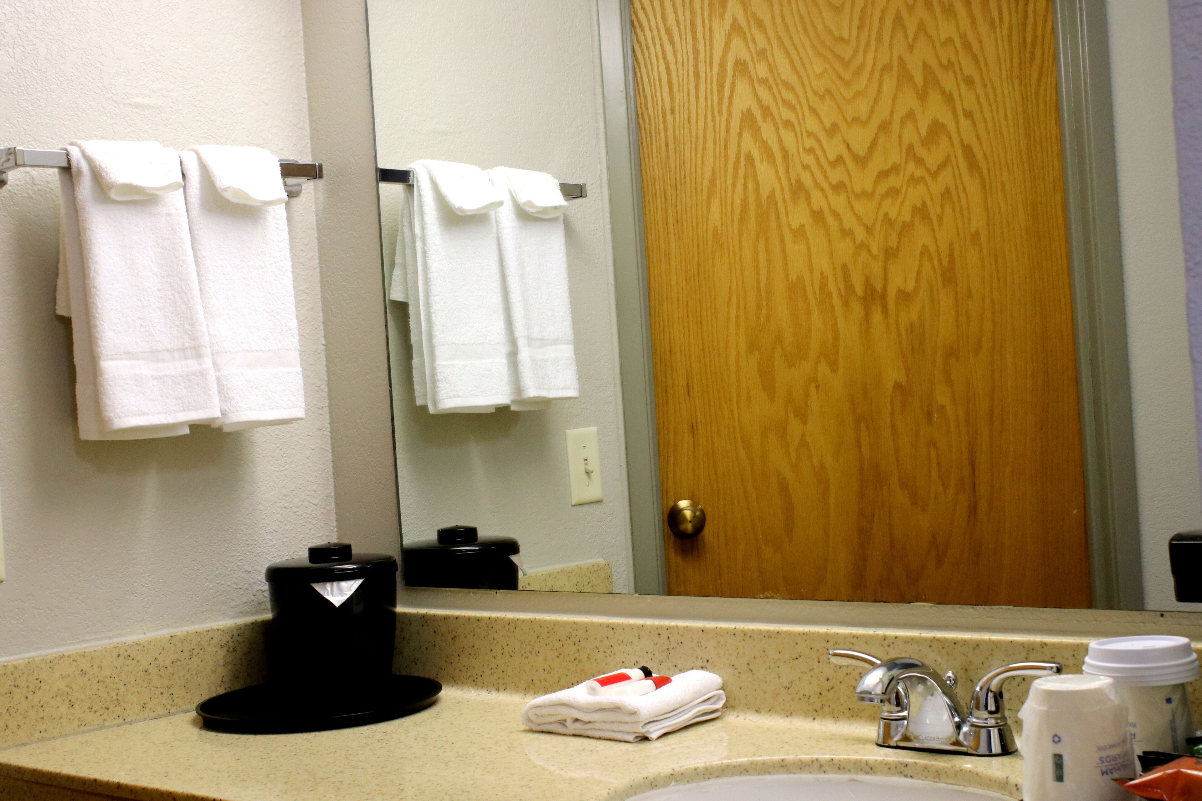 Une salle de bain avec un lavabo, un miroir et des serviettes accrochées au mur.