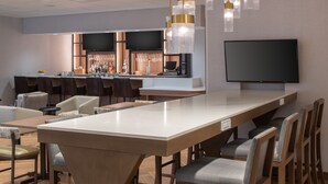 A modern bar area with a long counter, multiple bar stools, and a flat-screen TV mounted on the wall. - Fairfield Inn by Marriott Issaquah (Issaquah)