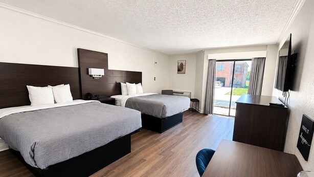 A hotel room with two beds, a desk, a TV, and a large window. - Quality Inn Harrodsburg (Harrodsburg)
