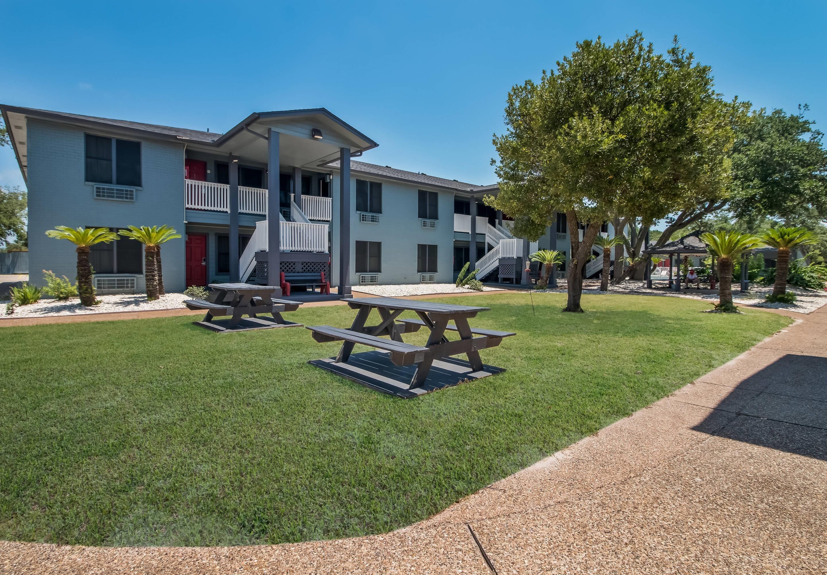 A two-story building with a balcony, picnic tables, and a well-maintained lawn.