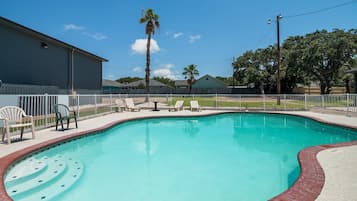 Una piscina al aire libre, sillones reclinables de piscina