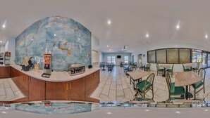 A spacious lobby with a marble reception desk, seating area, and a large glass window.