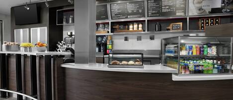A modern reception area with a curved counter, a digital menu board, and a beverage display.