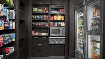 Eine Küche mit integriertem Mikrowellenherd, Regalen voller Snacks und einem Kühlschrank.