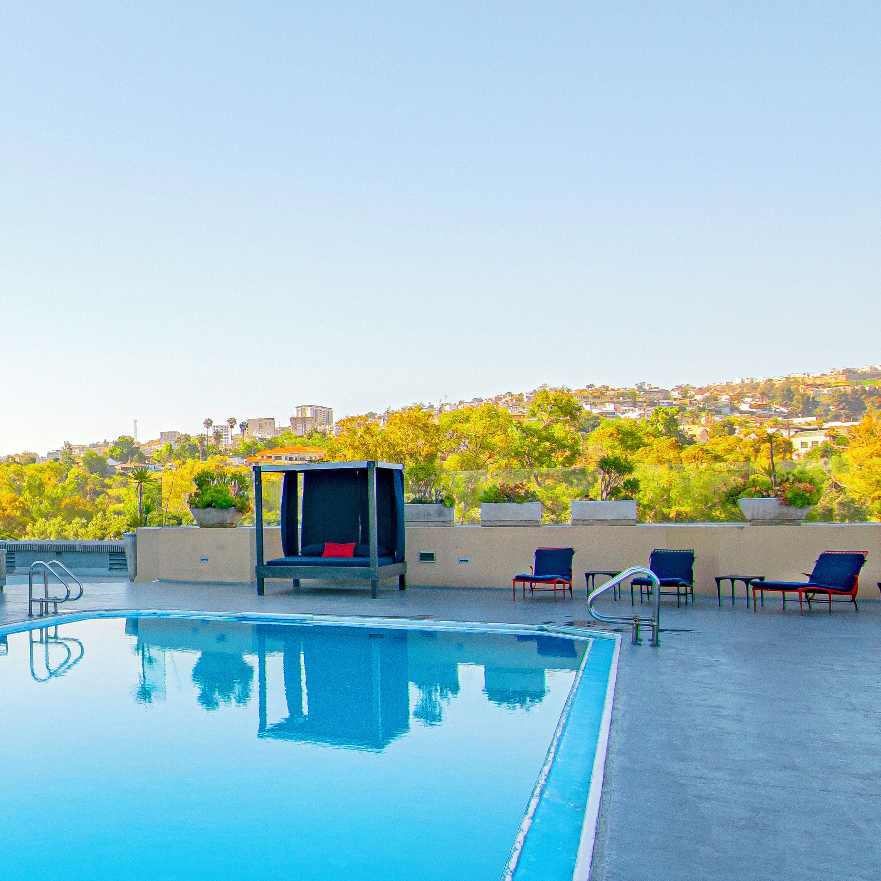 A rooftop pool with a seating area and lounge chairs.