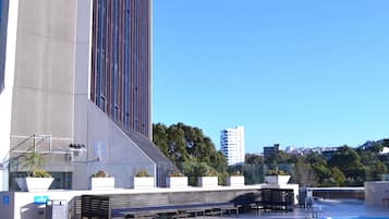 Hotel features a modern facade with a series of windows, adjacent to a swimming pool and lounge area.