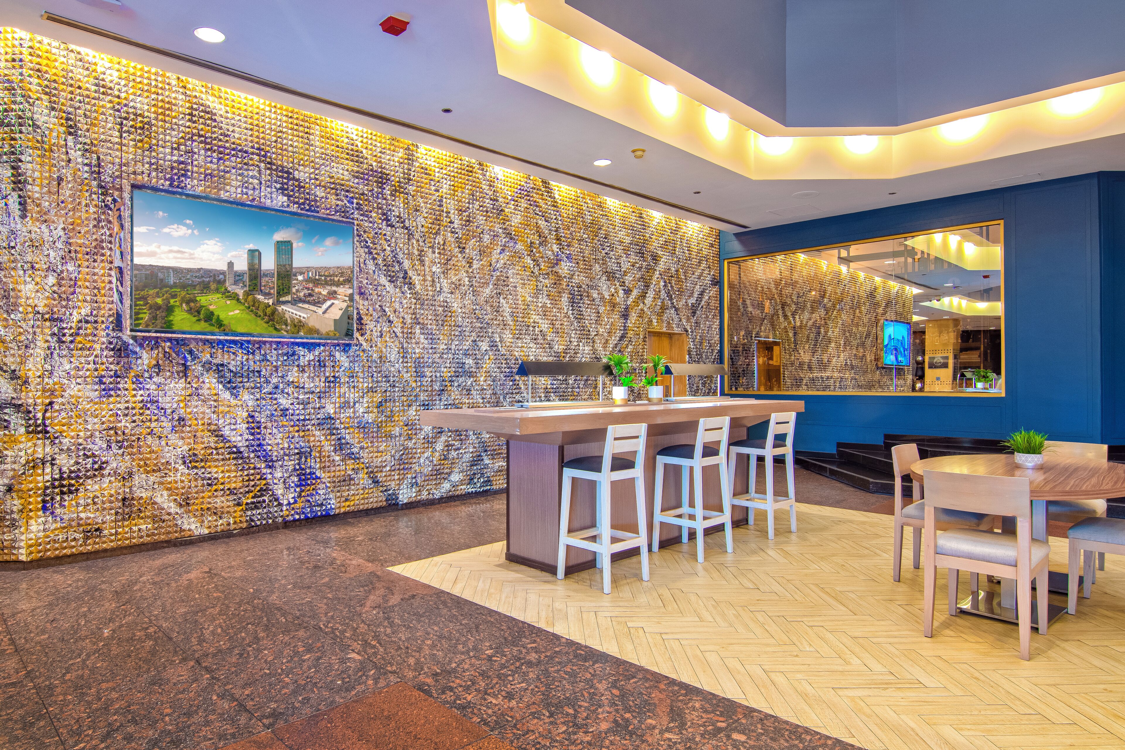 A modern lobby with a mosaic wall, a reception desk, and seating area.