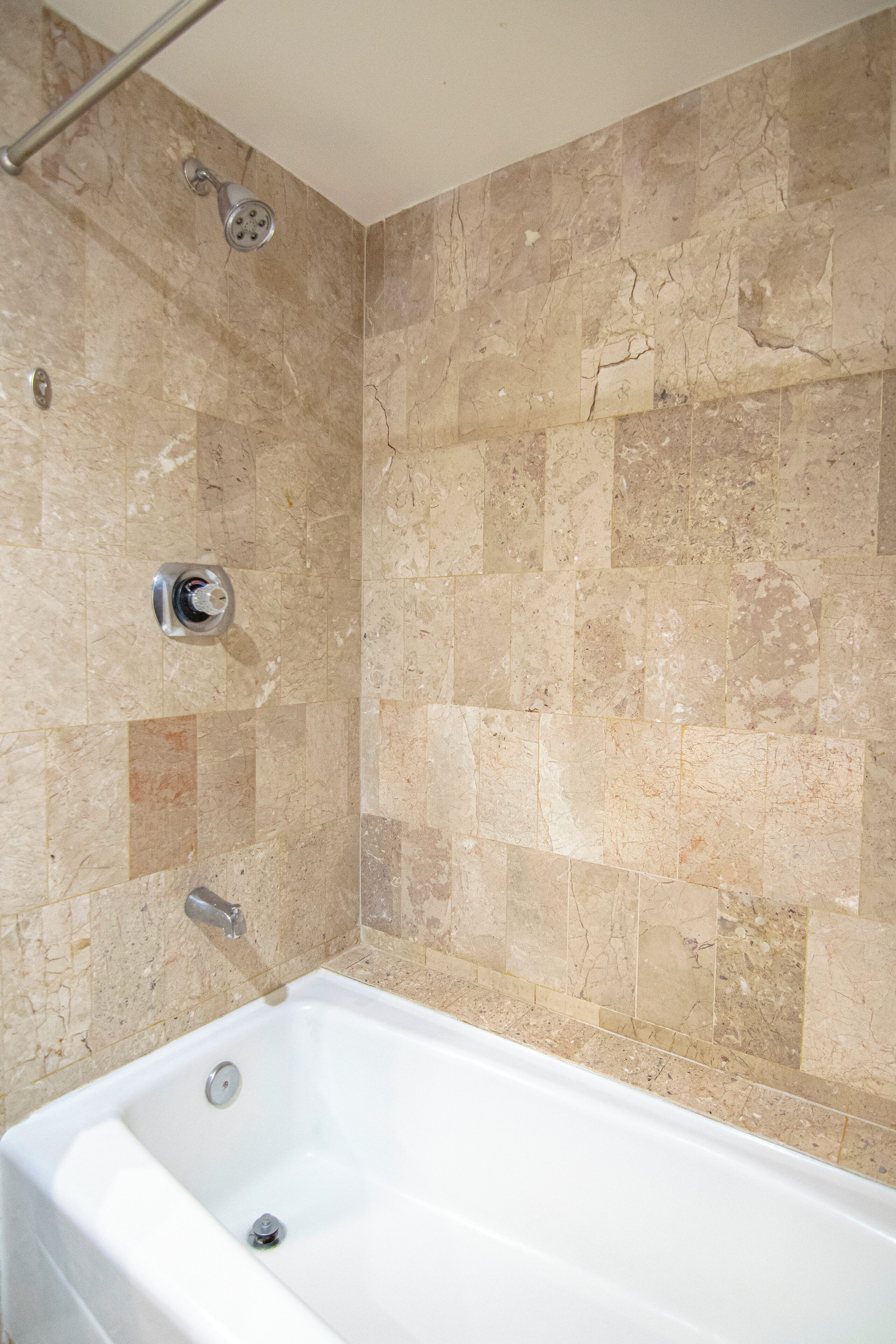 A bathroom with a bathtub, tiled walls, and a showerhead.