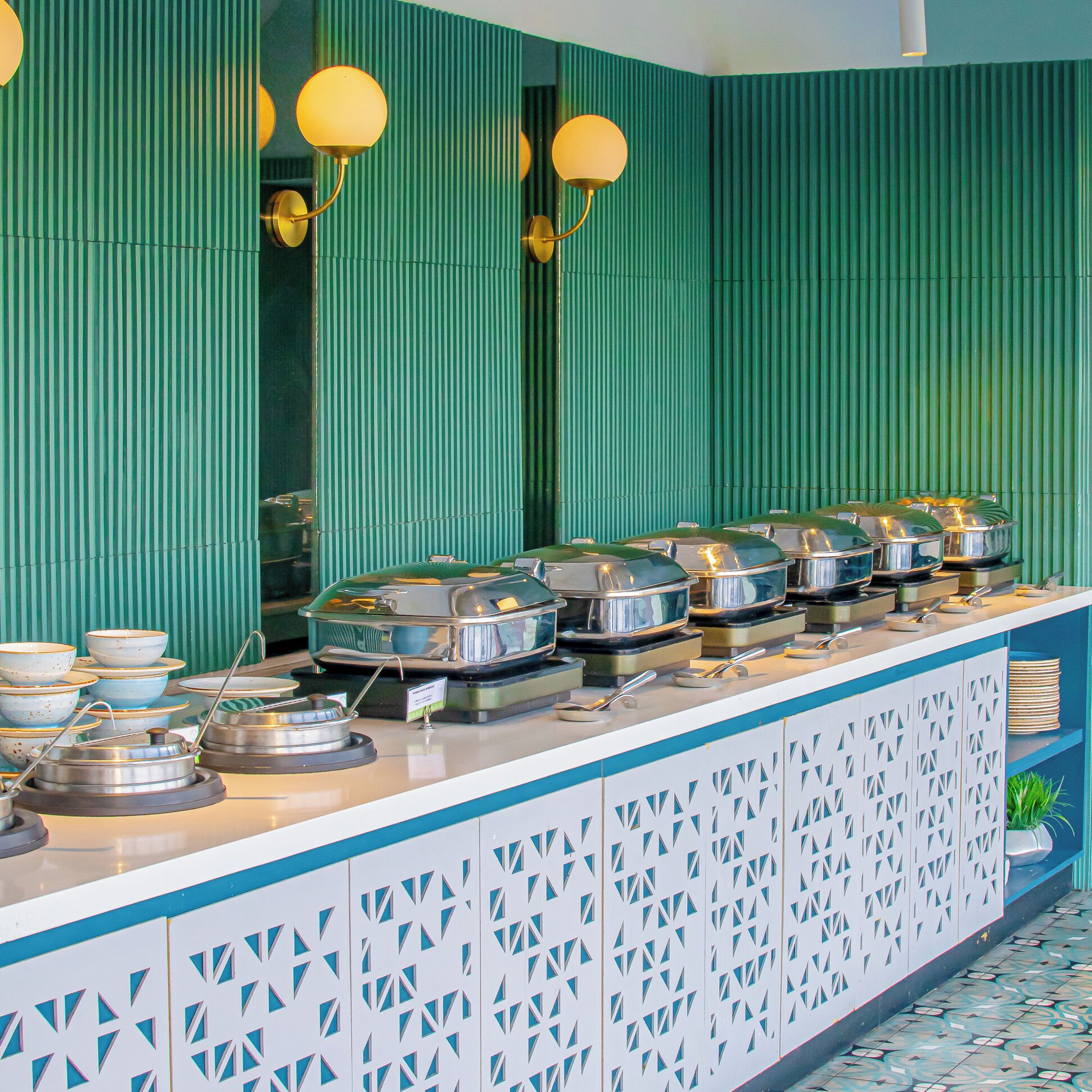A buffet counter with multiple serving stations, each with covered dishes and utensils.
