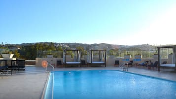 Una piscina en la azotea con sillones de descanso y vistas de la ciudad.