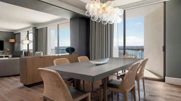 A modern dining area with a large table, wicker chairs, a central island, and a decorative chandelier.