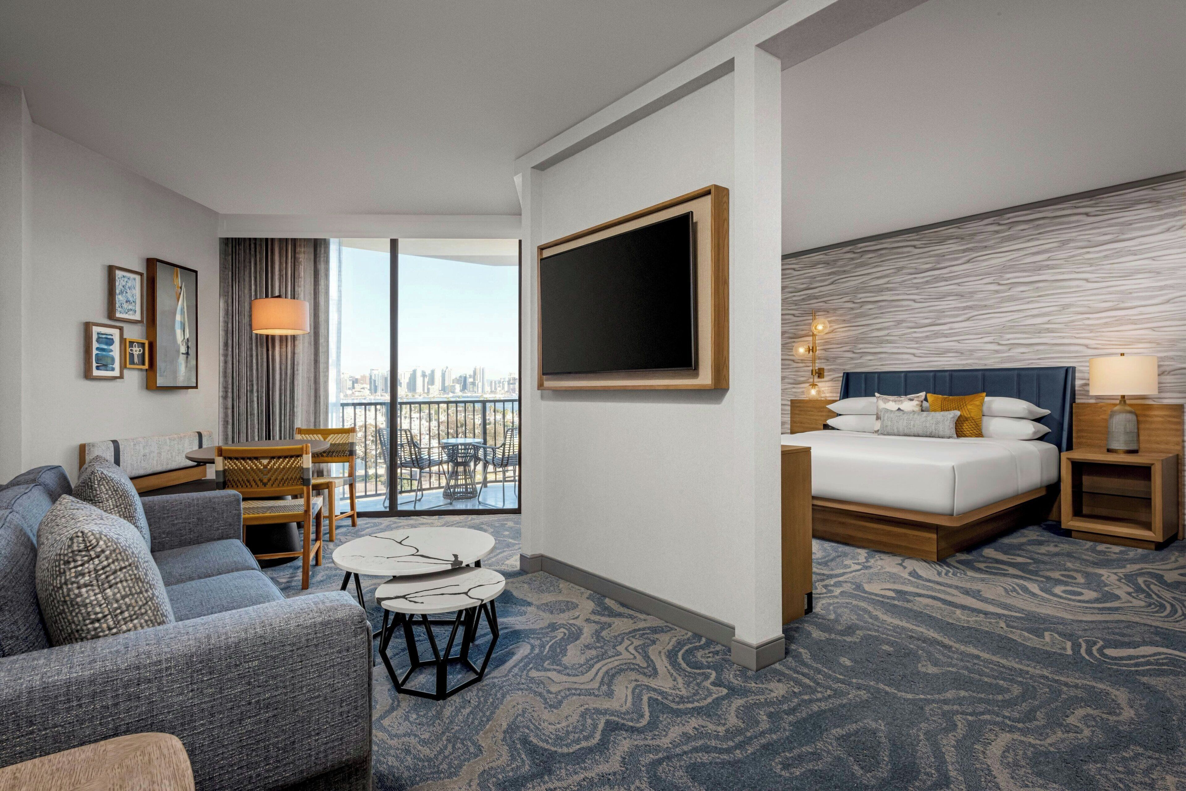 Una habitación de hotel con una cama grande, un sofá, una mesa de comedor y vistas a la ciudad.