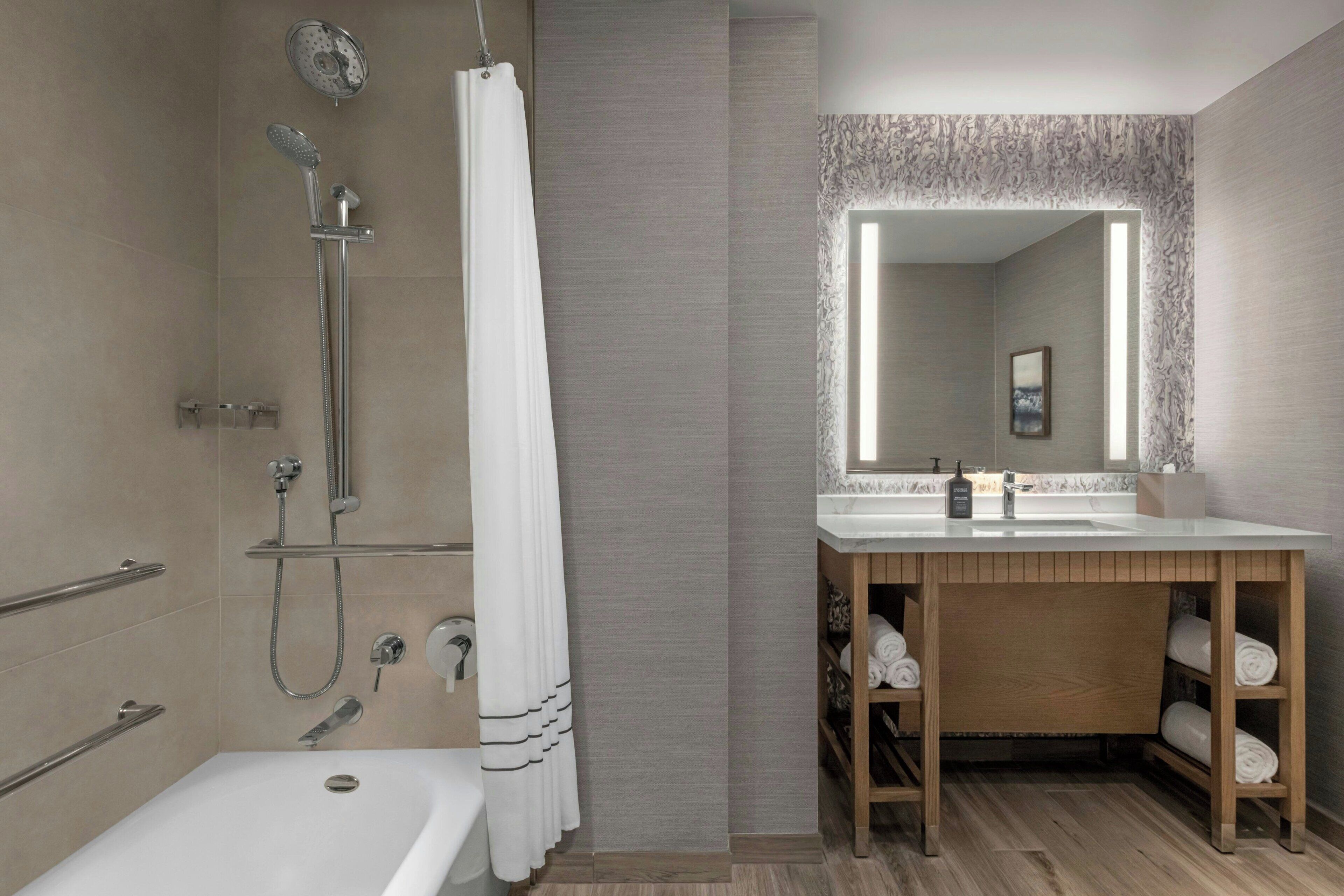 A modern bathroom with a shower, a bathtub, and a vanity with a mirror.