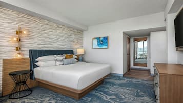 Ein Hotelzimmer mit Bett, Nachttisch, Lampe, einem Gemälde und einem Fernseher.
