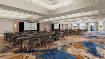 A Sheraton San Diego Resort conference room with a large screen, rows of tables and chairs, and a patterned carpet.