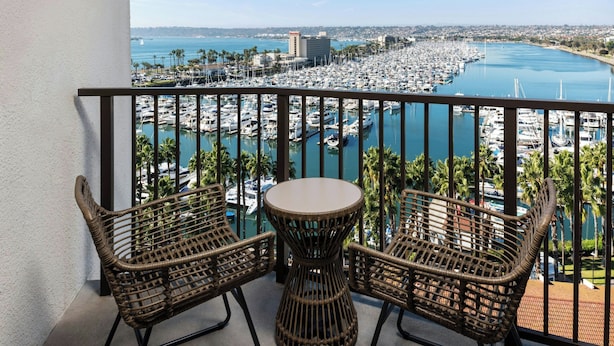 A balcony with wicker furniture overlooking a marina and a coastal cityscape. - Sheraton San Diego Resort (San Diego)