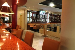 L’intérieur d’un restaurant avec des banquettes, un coin bar et un écran de télévision.