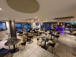 Un amplio espacio interior con varias mesas y sillas dispuestas para comer o conversar.