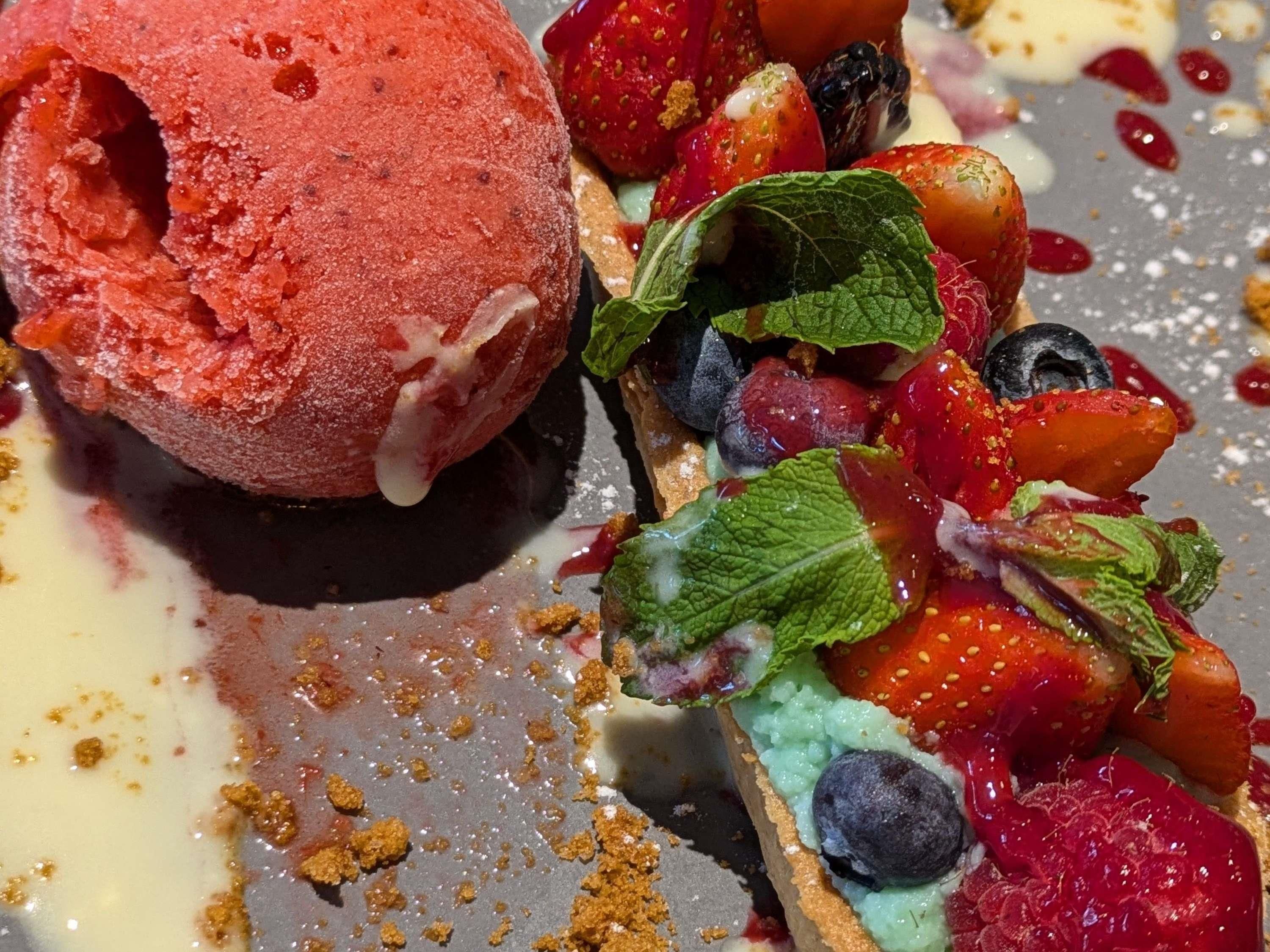 A dessert with ice cream and fresh berries on a plate.