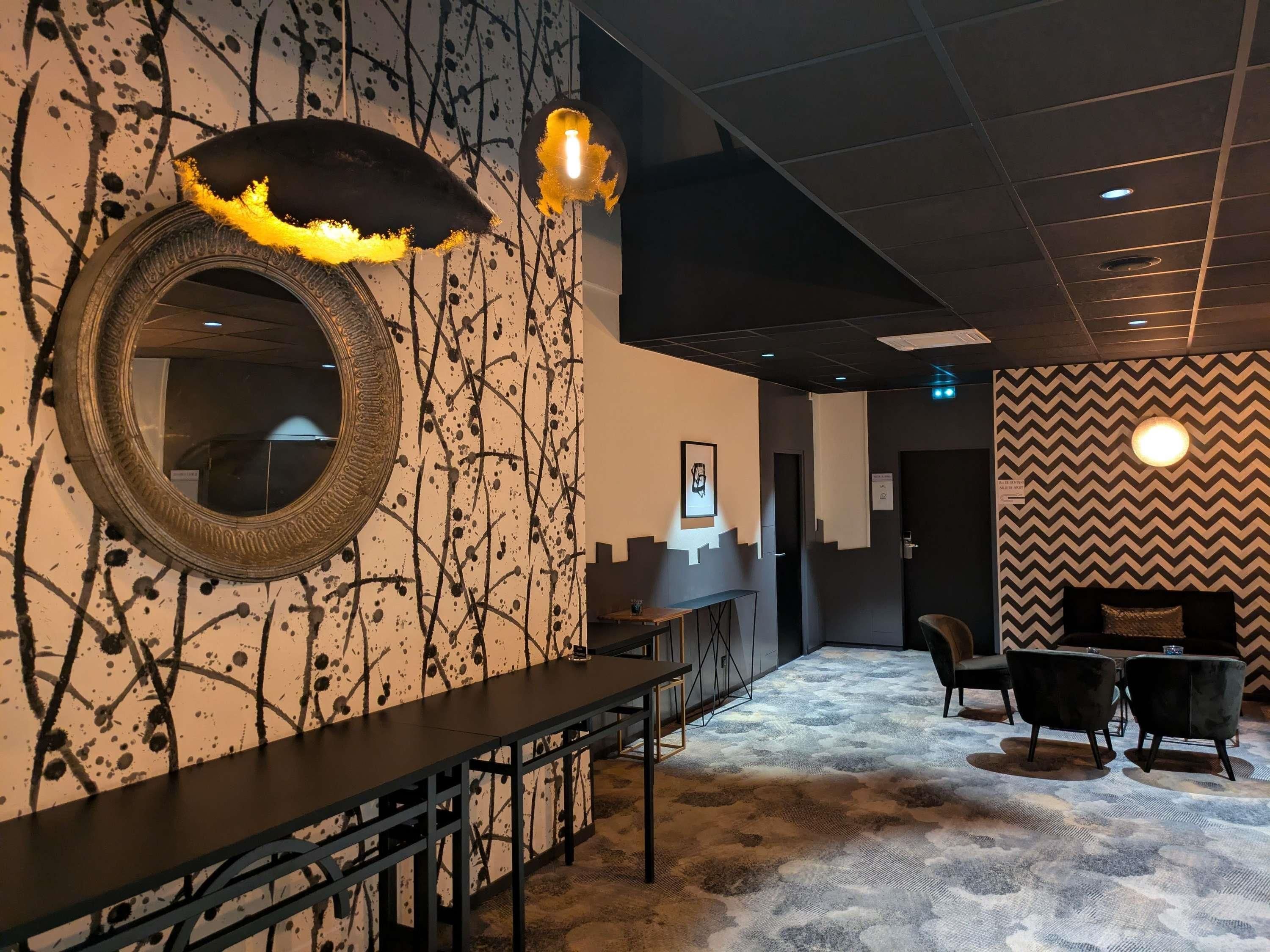 Un vestíbulo de hotel con un mostrador de recepción alargado, un espejo y una zona de estar con sillas.