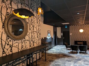 A hotel lobby with a long reception desk, a mirror, and a seating area with chairs. - Mercure Pau Palais Sports (Pau)