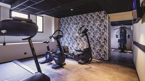 A gym with a treadmill, elliptical, and weight machine. - Mercure Pau Palais Sports (Pau)