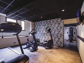 Un gimnasio con cinta de correr, elíptica y máquina de pesas.