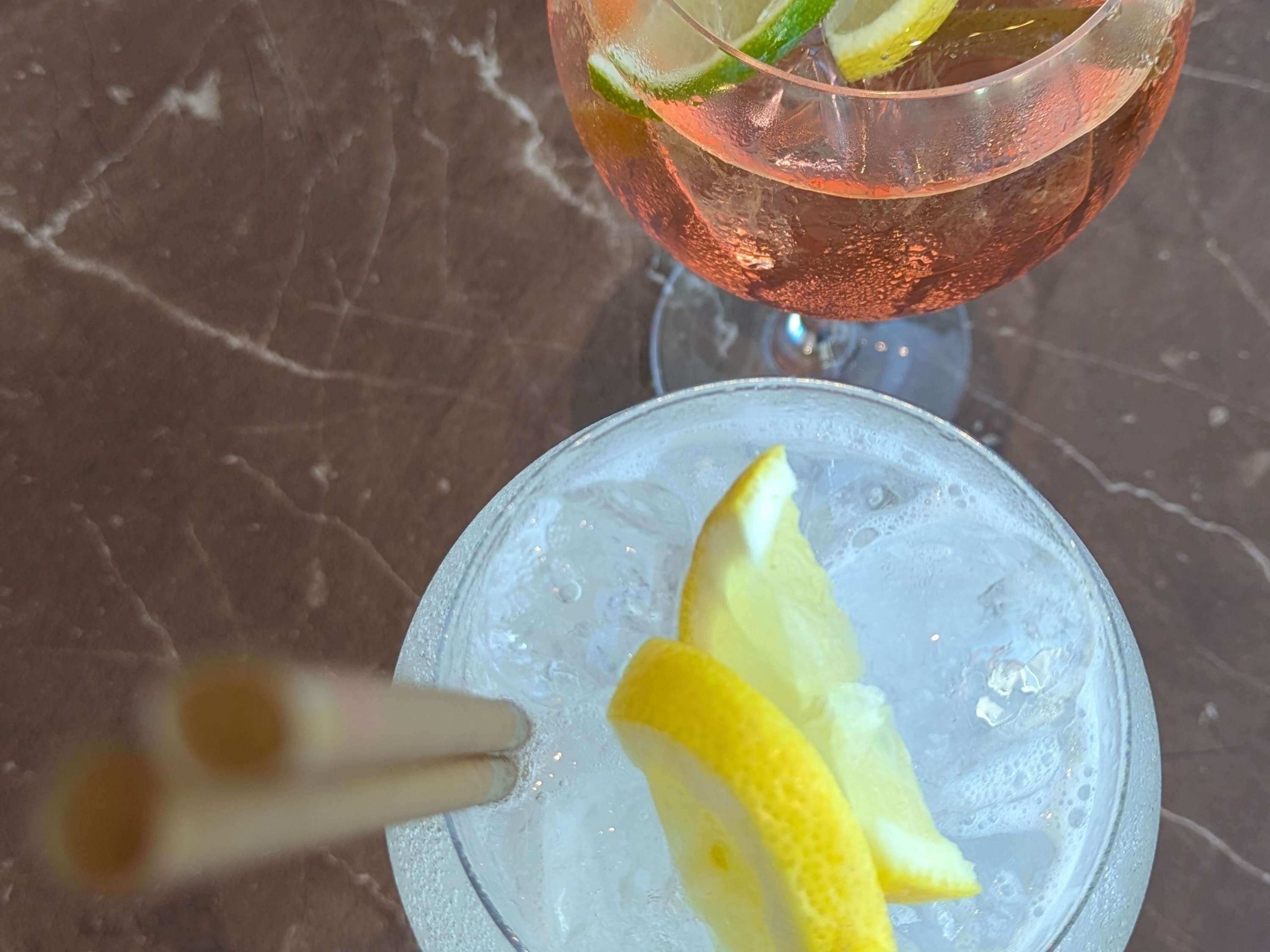 Two glasses of a pink beverage with lime garnish on a marble surface.