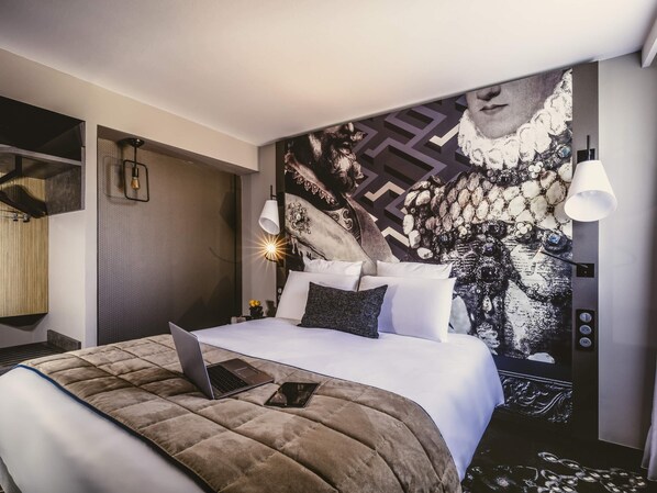 A modern hotel room with a large bed, a laptop on the bed, and a decorative wall mural. - Mercure Pau Palais Sports (Pau)