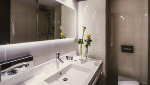 A modern bathroom with a large mirror, a white sink, and a glass shower enclosure. - Mercure Pau Palais Sports (Pau)