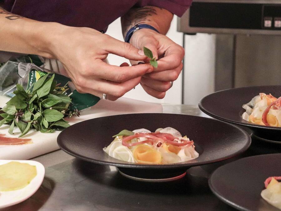 A person preparing food, specifically arranging leaves on a dish.