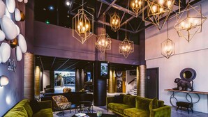 En moderne lobby med grønne sofaer, et sofabord og geometrisk hængende belysning.