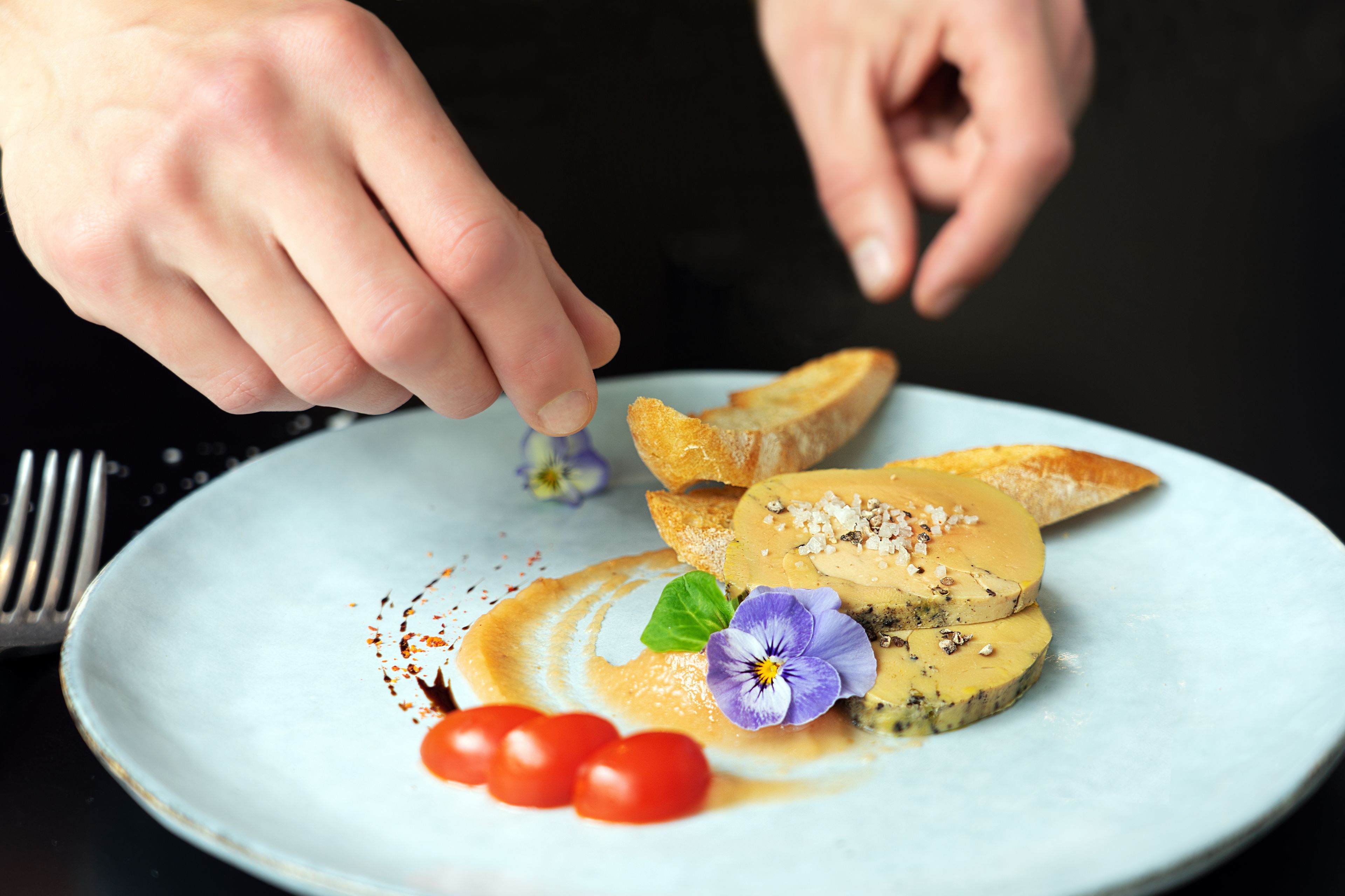 A plate with a slice of cheese, cherry tomatoes, and a flower garnish.