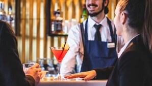 En bar med en bartender, der serverer en cocktail.