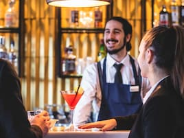 Un bar con un cantinero sirviendo un cóctel.