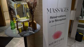 A reception area with a sign for massages and a table with a vase of flowers and a fish tank.