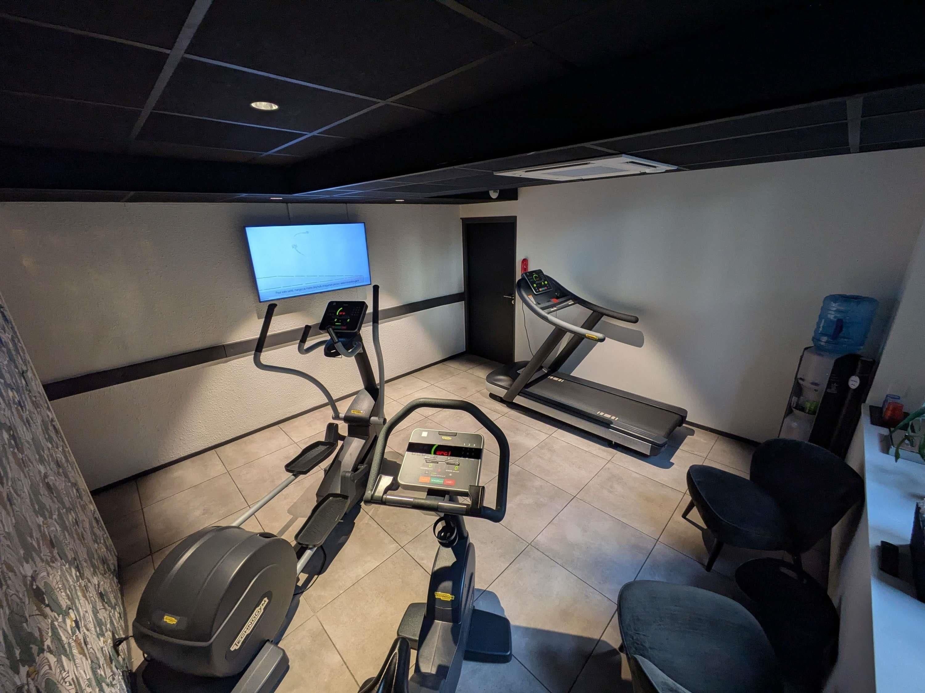 A gym with exercise equipment, a television, and a water dispenser.