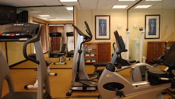 Un gimnasio con máquinas de cardio, espejos y obras de arte enmarcadas en las paredes.
