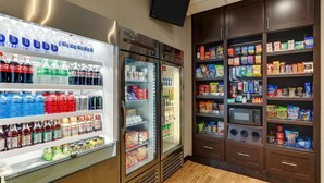 A hotel room with a minibar stocked with beverages and snacks, a television mounted on the wall, and a microwave in the cabinet. - Drury Inn & Suites Phoenix Airport (Phoenix)