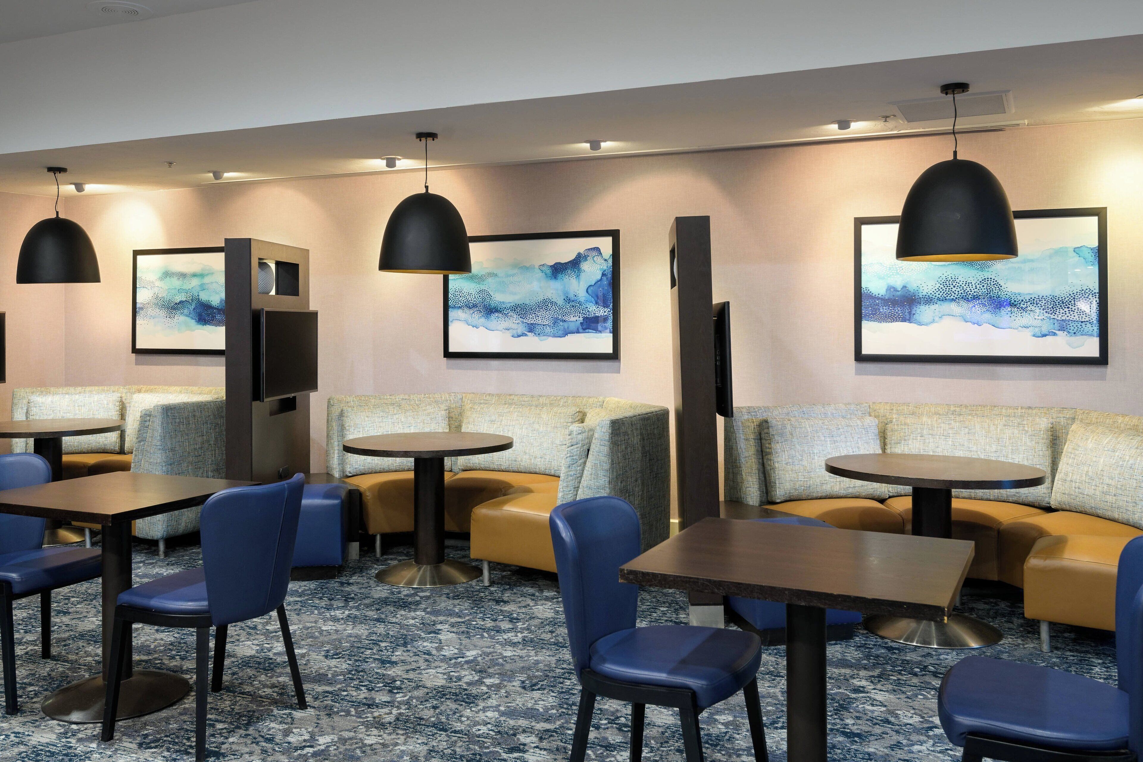 A modern hotel lobby with seating areas, tables, and artwork on the walls.