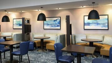 A modern hotel lobby with seating areas, tables, and artwork on the walls.