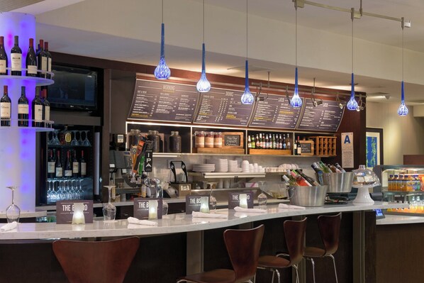 Un espace bar avec de nombreuses bouteilles de vin, un tableau affichant le menu et des tabourets de bar.